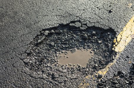 Close-up of the effects of road weathering and neglect – a deep pot hole causing a danger to drivers.